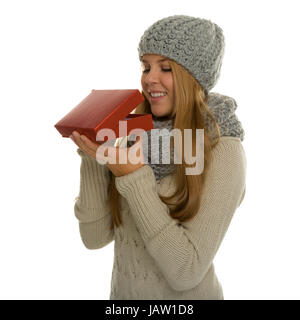 Junge Frau / Mädchen trägt Strickware und schaut erwartungsvoll in eine Geschenkverpackung. Vielleicht eine Überraschung zu Weihnachten oder ein Geschenk im neuen Jahr Stock Photo