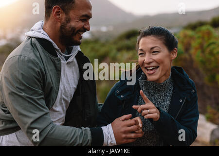 Portrait of couple of happy hikers walking in the countryside. Young man and woman having fun outdoors on a vacation. Stock Photo
