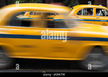 An iconic yellow taxi drives down a road in Kolkata (Calcutta), West Bengal, India India Stock Photo