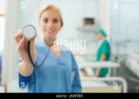 Focus on a nurse holding a stethoscope in hospital ward Stock Photo