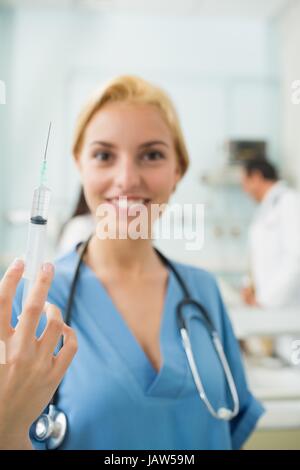 Focus on a blonde nurse holding a syringe Stock Photo