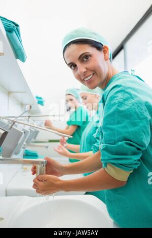 Surgeon rinsing hands while looking at camera Stock Photo