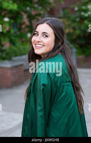 Female college student in a natural light lifestyle portrait while wearing her graduation gown right before graduating from a university. Stock Photo