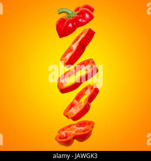 Creative concept with flying orange paprika. Sliced floating bell pepper on an orange background Stock Photo