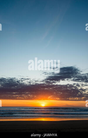 Sunset sinks into a broad horizon over the southern ocean. Stock Photo