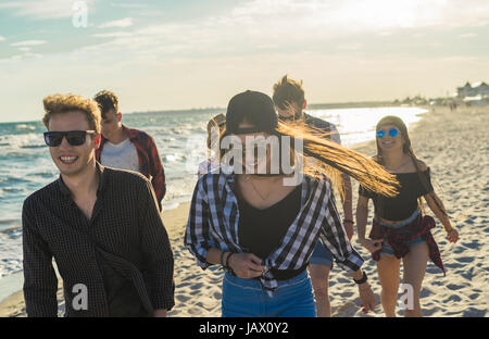 Group of hipster young friends running along beach together Stock Photo
