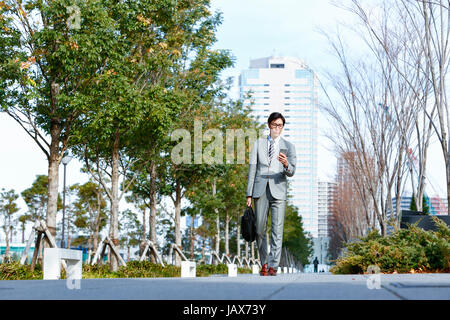 Japanese businessman with smartphone downtown Tokyo, Japan Stock Photo