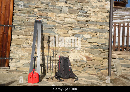 Pair of tour ski with backpack and light shovel for avalanche rescue on old stone wall of alpine hut in the italian Alps Stock Photo