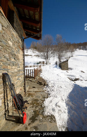Pair of tour ski with backpack and light shovel for avalanche rescue on old stone wall of alpine hut in the italian Alps Stock Photo