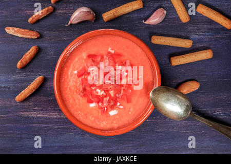 A photo of gazpacho, traditional Spanish cold soup, with bread sticks shot from above on a deep purple wooden texture with a place for text Stock Photo