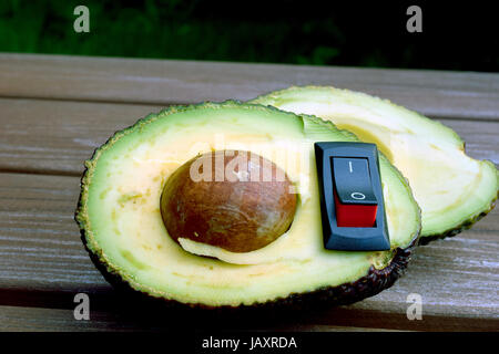 Avocado with inserted power switch. Concept of healthy food. Stock Photo