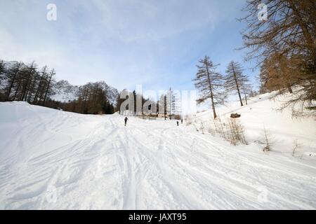 Off piste ski slope with ski tracks, some hikers and scenic valley in the italian Alps Stock Photo