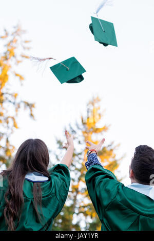 Two college students throw their caps in the air during graduation ceremonies at a university in Oregon. Stock Photo