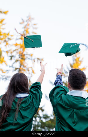 Two college students throw their caps in the air during graduation ceremonies at a university in Oregon. Stock Photo