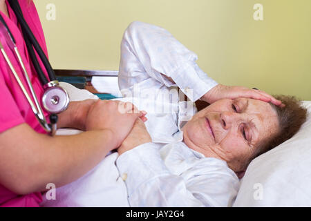 Picture of a bedridden old woman having a headache Stock Photo