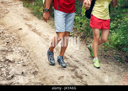 Young couple hikers in forest. sports man and woman with backpacks on road in nature. legs closeup Stock Photo