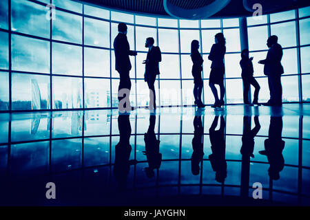 Several white collar workers communicating in office against window Stock Photo
