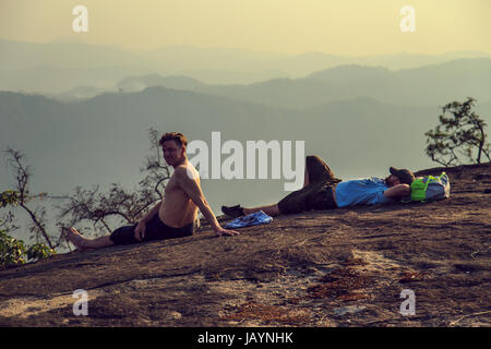 Group of tourists watching the sunset on top of the mountain. Rest after climbing. Stock Photo