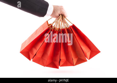 Man's arm in a suit and white shirt holding six red shopping bags on a white background Stock Photo