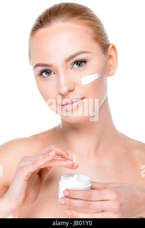 portrait of woman applying face cream and looking to camera on white Stock Photo