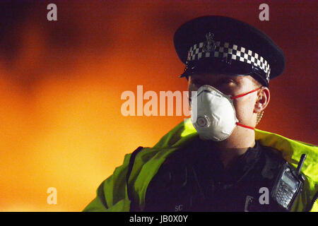 A Police Officer at the scene of a fire wearing a protective mask. Stock Photo