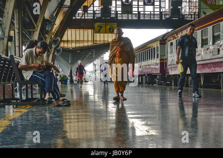 Hua Lamphong train station in Bangkok, Thailand. A monk and other travellers on platform with stationery train. Stock Photo