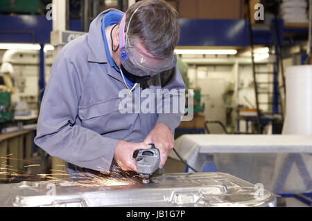 factory floor worker using a angle grinder on metal surface Stock Photo