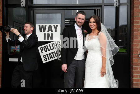 Alliance candidate for West Belfast Sorcha Eastwood casts her vote in the 2017 General Election, with her husband, Dale Shirlow, at a polling station in Lisburn, Northern Ireland, still wearing her wedding dress after they were married earlier in the day. Stock Photo