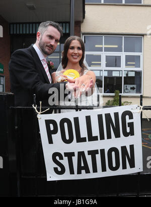 Alliance candidate for West Belfast Sorcha Eastwood casts her vote in the 2017 General Election, with her husband, Dale Shirlow, at a polling station in Lisburn, Northern Ireland, still wearing her wedding dress after they were married earlier in the day. Stock Photo