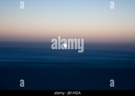 This is a multiple exposure of the Pacific Ocean at dusk with the moon in the center. Stock Photo