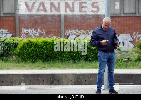 Man using a mobile phone the train station platform, Vannes, France Stock Photo