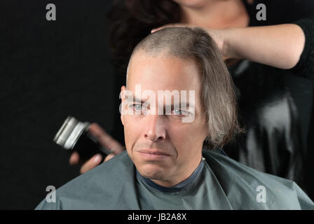 Close-up of a mourning man getting his long hair is shaved off for a cancer fundraiser. Stock Photo