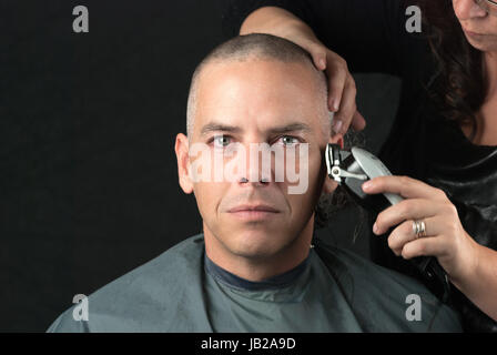 Close-up of a mourning man getting his head shaved. Looking to camera, Stock Photo