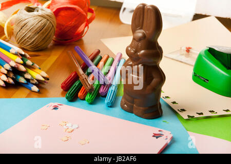 pens lie on a table , a chocolate bunny and craft materials Stock Photo