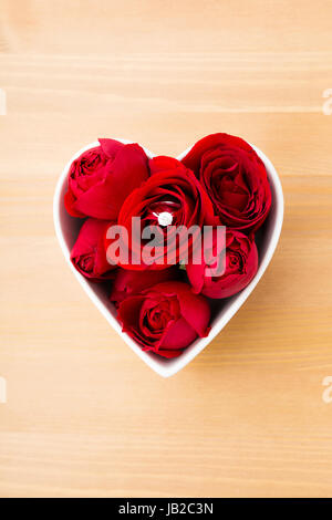 Red rose and diamond ring inside heart shape bowl Stock Photo