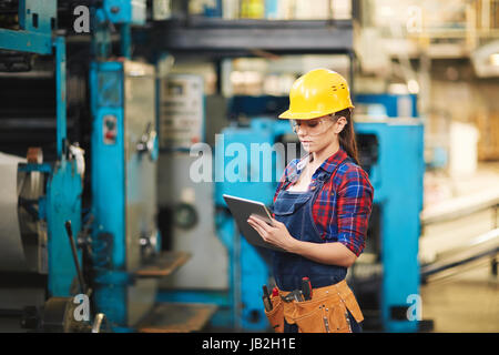 Female Technician Inspecting Machine Stock Photo
