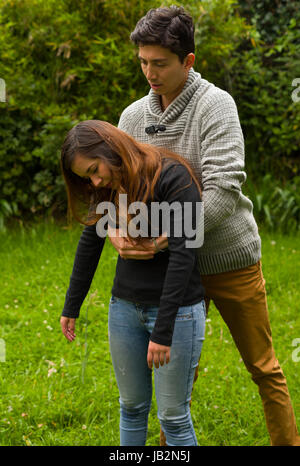 Handsome young man well dressed doing the first aid to a beautiful woman, cardiopulmonary resuscitation concept, in a backyard background. Stock Photo