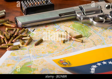 Close up of a shotgun and a revolver, cartridge belt with bullets with a blurred Venezuelan flag, on wooden table. Stock Photo