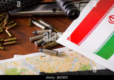 Close up of a shotgun and a revolver, cartridge belt with bullets with an Iran flag on a map, on wooden table. Stock Photo