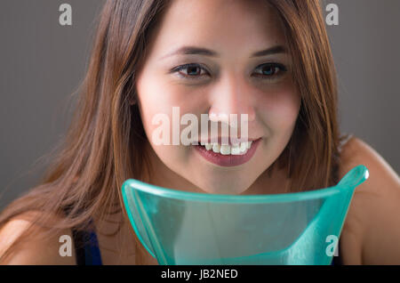 Young woman doing inhalation with a medical vaporizer nebulizer machine on grey background. Stock Photo