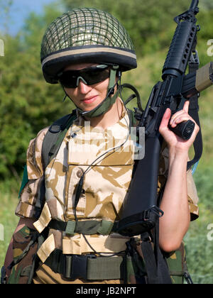 British girl soldier in desert uniform holding her rifle Stock Photo