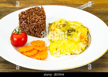 Fish fillet in creamy sauce with vegetables, red rice. Studio Photo Stock Photo