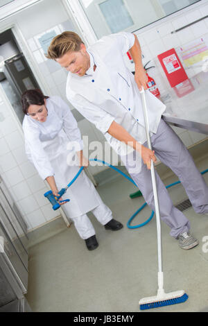 restaurant employees cleaning the kitchen floor Stock Photo