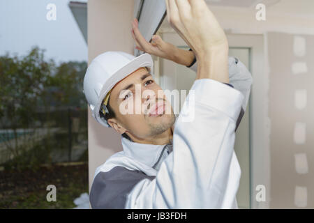 young man taping up windows in for a hurricane Stock Photo