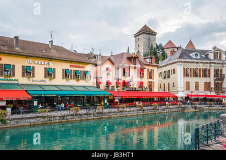 Restaurants and cafes with colourful red and green awnings in historic buildings along the bank of the Thiou river in the old town of Annecy, France Stock Photo