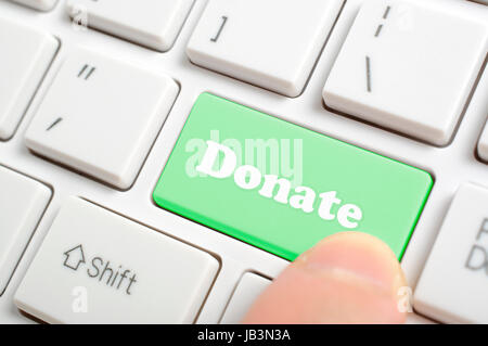 Pressing green donate key on keyboard Stock Photo