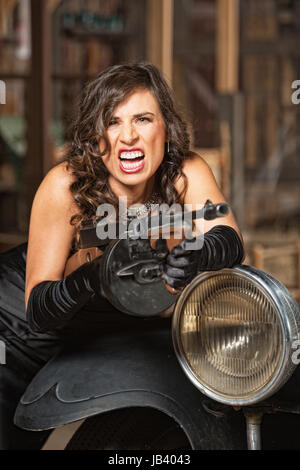 Aggressive 1920s female gangster shooting submachine gun Stock Photo