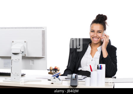Junge, hübsche Büroangestellte sitzt am Schreibtisch im Büro und telefoniert mit einem Smartphone Stock Photo