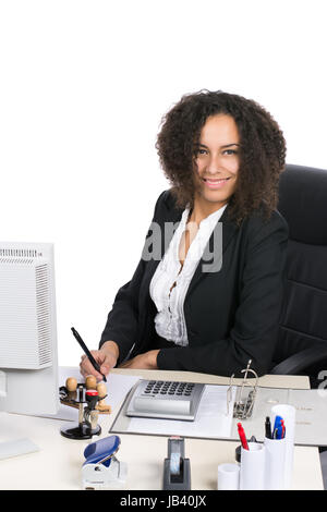 Junge, hübsche Angestellte sitzt am Schreibtisch im Büro und schreibt auf einem Blatt Papier Stock Photo