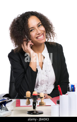 Junge, hübsche Geschäftsfrau sitzt am Schreibtisch im Büro und telefoniert mit einem Smartphone Stock Photo